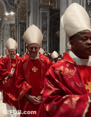 A Group Of Priests Are Walking In A Church And One Of Them Has A Cross On His Vest GIF