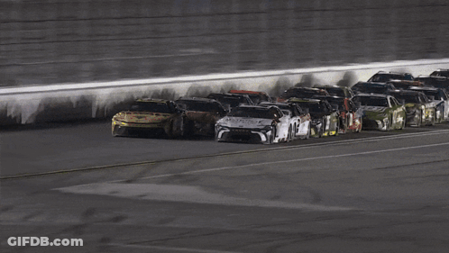 A Group Of Race Cars Are Lined Up On A Race Track GIF