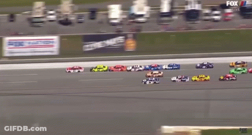 A Group Of Race Cars Are Racing On A Track With A Fox Live Advertisement Behind Them GIF