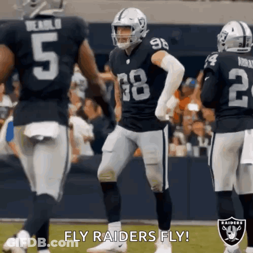 A Group Of Raiders Football Players Are Standing On A Field During A Game . GIF