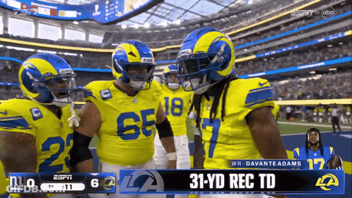A Group Of Rams Football Players Are Standing On The Field GIF