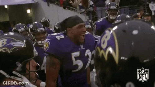 A Group Of Ravens Football Players Are Huddled Together . GIF