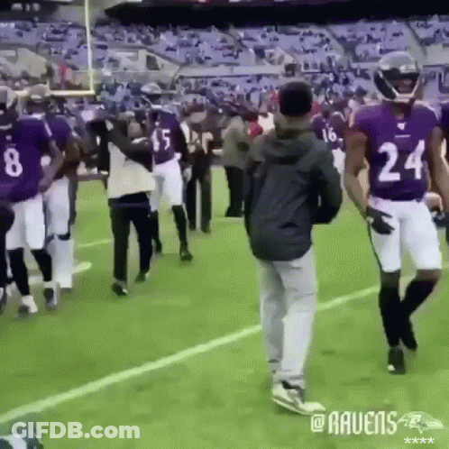 A Group Of Ravens Players Are Walking On The Field GIF
