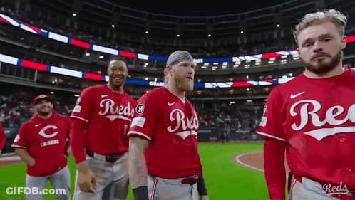 A Group Of Reds Baseball Players Are Standing On The Field . GIF