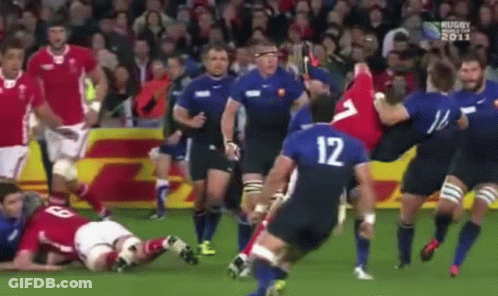 A Group Of Rugby Players Are Playing A Game On A Field . One Of The Players Has The Number 12 On His Jersey . GIF