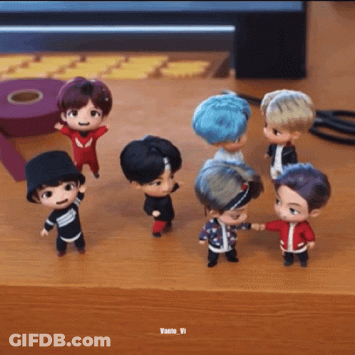 A Group Of Small Dolls Are Standing On A Wooden Table . GIF
