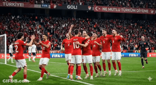 A Group Of Soccer Players Are Celebrating A Goal On A Field GIF