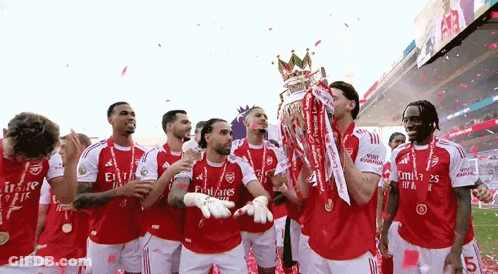 A Group Of Soccer Players Are Celebrating With A Trophy On A Field . GIF