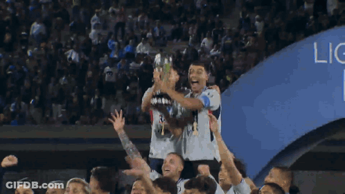 A Group Of Soccer Players Are Holding Up A Trophy In The Air GIF