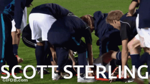 A Group Of Soccer Players Are Huddled Around Scott Sterling On The Field GIF