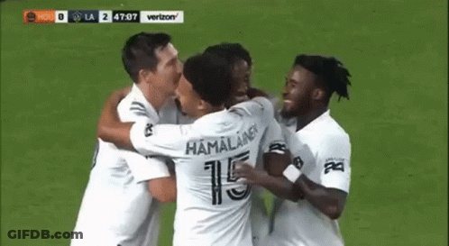 A Group Of Soccer Players Are Hugging And Celebrating A Goal . GIF