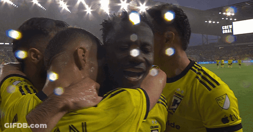 A Group Of Soccer Players Are Hugging Each Other In Front Of A Scoreboard That Says " Crew Goal " GIF