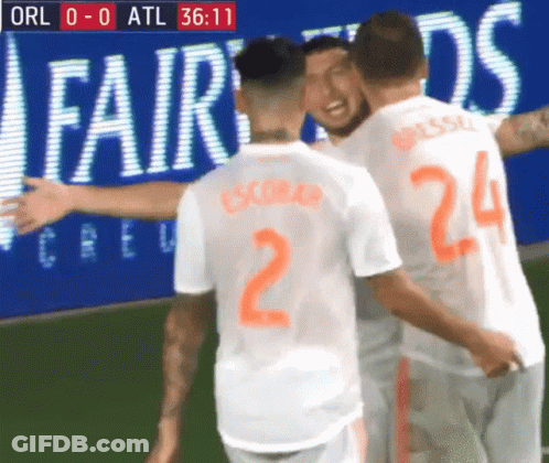 A Group Of Soccer Players Are Hugging Each Other In Front Of An Ad For Fairwinds GIF