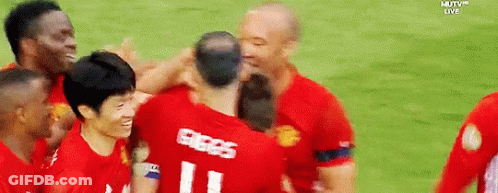 A Group Of Soccer Players Are Hugging Each Other On A Field With Mutv Live In The Background GIF