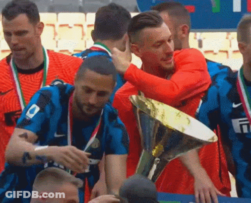 A Group Of Soccer Players Are Hugging Each Other While Holding A Trophy . GIF