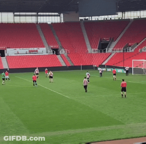 A Group Of Soccer Players Are Playing On A Field In Front Of Empty Stands GIF
