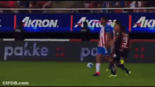 A Group Of Soccer Players Are Playing On A Field With An Ad For Akron Behind Them GIF