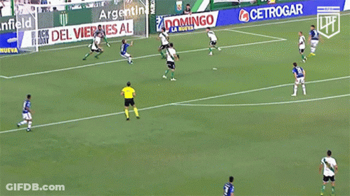 A Group Of Soccer Players Are Playing On A Field With An Advertisement For Banfield Behind Them GIF