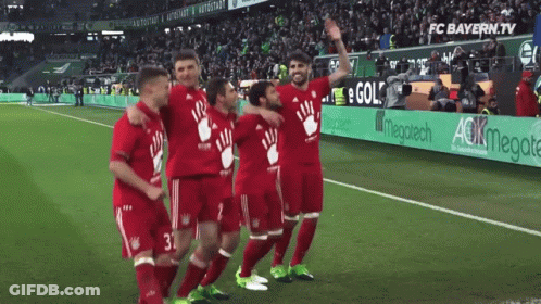 A Group Of Soccer Players Are Posing For A Picture On A Field With An Ad For Fc Bayern.tv In The Background GIF