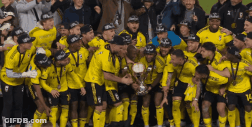 A Group Of Soccer Players Are Posing For A Picture With A Trophy That Says Champions On It GIF