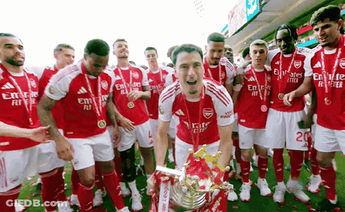 A Group Of Soccer Players Are Posing With A Trophy On The Field . GIF