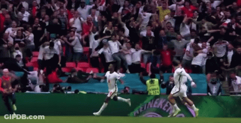 A Group Of Soccer Players Are Running On A Field In Front Of A Crowd Of People . GIF
