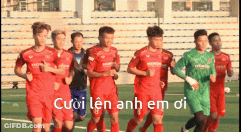 A Group Of Soccer Players Are Running On A Field With The Words Cuoi Len Anh Em Oi Written In White GIF