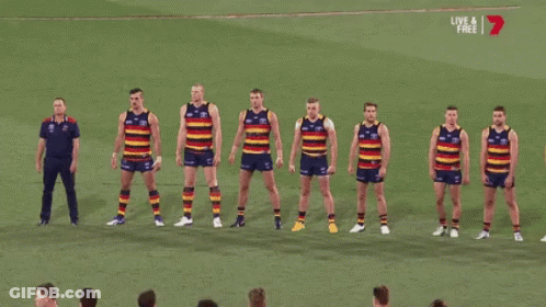 A Group Of Soccer Players Are Standing In A Row On A Field With A Live And Free Sign Above Them GIF