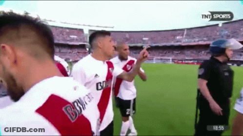 A Group Of Soccer Players Are Standing On A Field With A Police Officer In The Background GIF