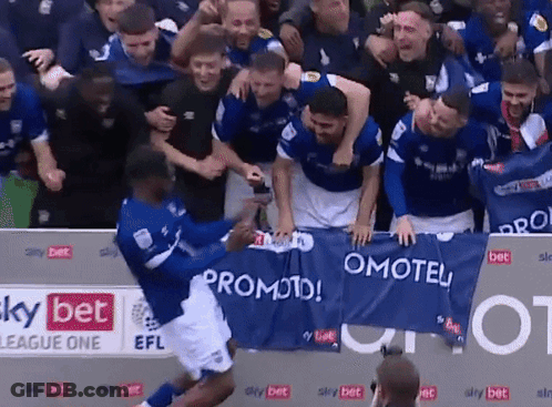 A Group Of Soccer Players Celebrate Behind A Banner That Says Promoted GIF