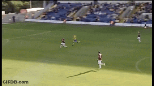 A Group Of Soccer Players On A Field With A Blue Bleacher In The Background GIF