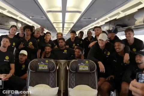 A Group Of Soccer Players Pose For A Picture On A Plane With A Seat That Says " Official Home Of Soccer " On It GIF