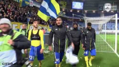 A Group Of Soccer Players Walking On A Field With A Fcsm Logo GIF