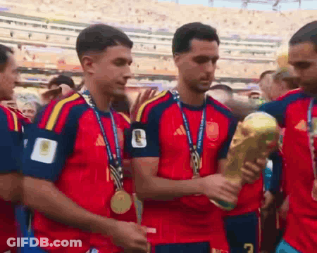 A Group Of Soccer Players With Medals Around Their Necks Are Holding A Trophy With The Number 7 On It GIF