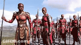 A Group Of Soldiers Are Marching Down A Road With Spears In Their Hands . GIF