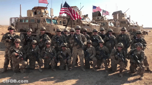 A Group Of Soldiers Are Posing For A Picture In Front Of A Military Vehicle That Says Stryker GIF