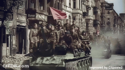 A Group Of Soldiers Are Riding On A Tank In Front Of A Building That Says Bianca GIF
