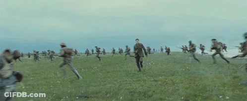 A Group Of Soldiers Are Running In A Field While An Explosion Takes Place . GIF