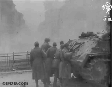 A Group Of Soldiers Are Standing Around A Destroyed Tank In A Black And White Photo Taken By Pathe GIF