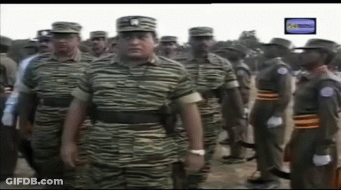 A Group Of Soldiers Are Standing In A Line With A TV Screen Behind Them GIF