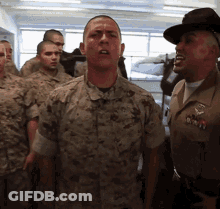 A Group Of Soldiers Are Standing In A Room And One Of Them Is Wearing A Hat That Says Us Marines GIF