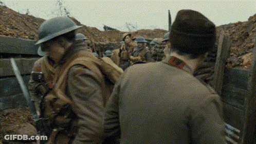 A Group Of Soldiers Are Standing In A Trench Talking To Each Other In A War Scene . GIF