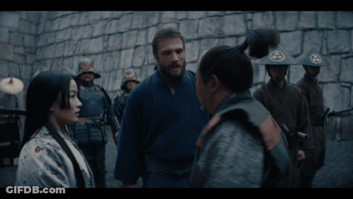 A Group Of Soldiers Are Standing In Front Of A Stone Wall And Talking To Each Other GIF