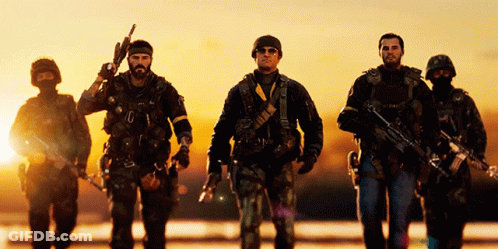 A Group Of Soldiers Are Walking In A Line With One Holding A Gun GIF