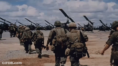 A Group Of Soldiers Are Walking In Front Of A Line Of Helicopters GIF