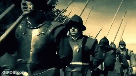 A Group Of Soldiers In Armor Are Marching In A Line With Spears And Shields . GIF