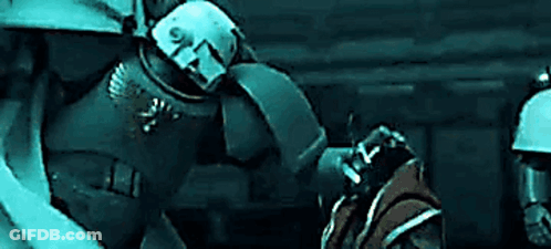 A Group Of Soldiers In Armor Are Standing In A Dark Room . GIF