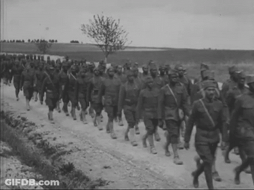 A Group Of Soldiers March Down A Dirt Road GIF