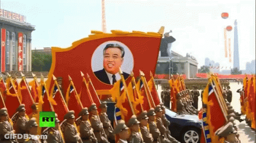 A Group Of Soldiers Marching With Flags And A Picture Of Kim Jong Un GIF