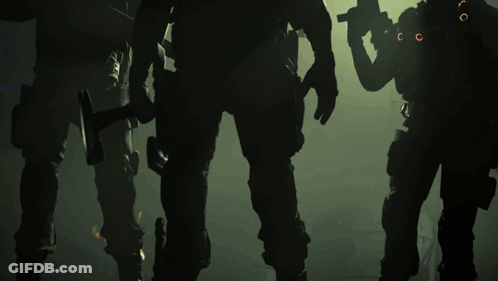 A Group Of Soldiers Standing In A Dark Room With A Hammer In Their Hand GIF